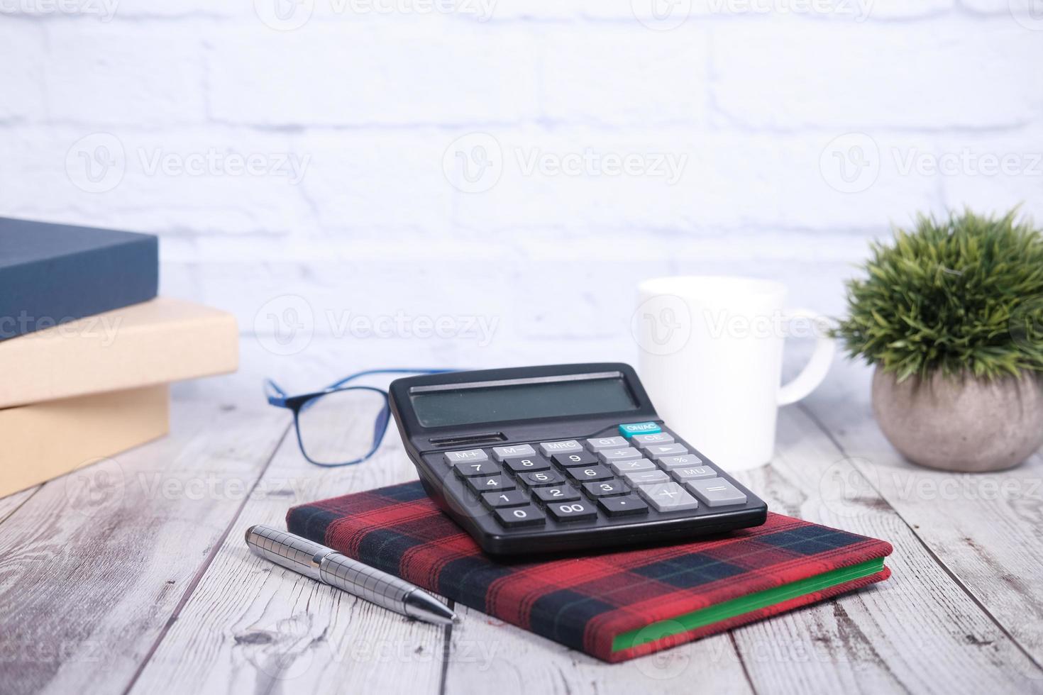 Notizblock, Taschenrechner, Stift auf Holzschreibtisch foto