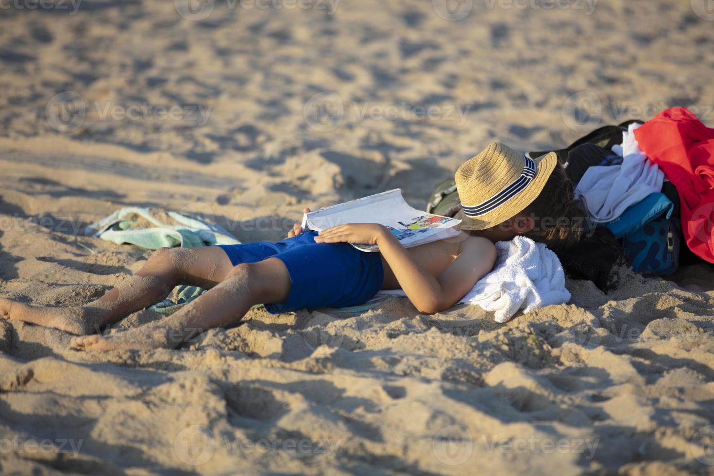 das Kind Lügen auf das Strand im das Sand. das Junge fiel schlafend auf das Strand. foto