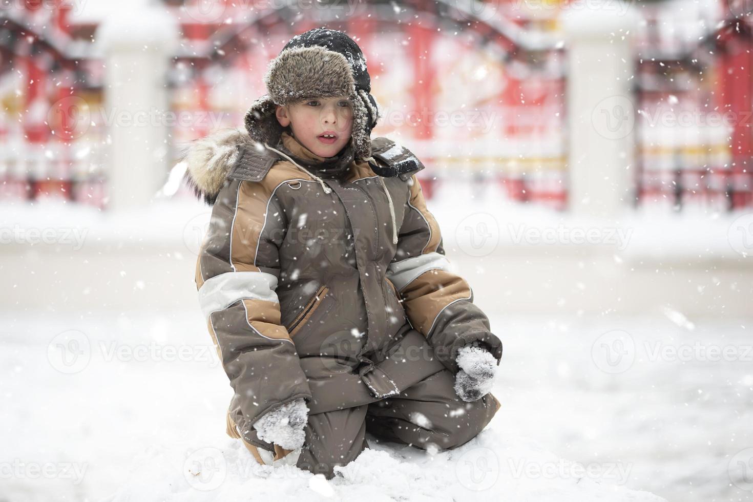 Kind im Winter im ein Schneewehe. ein Junge im Winter Kleider auf ein gehen. foto