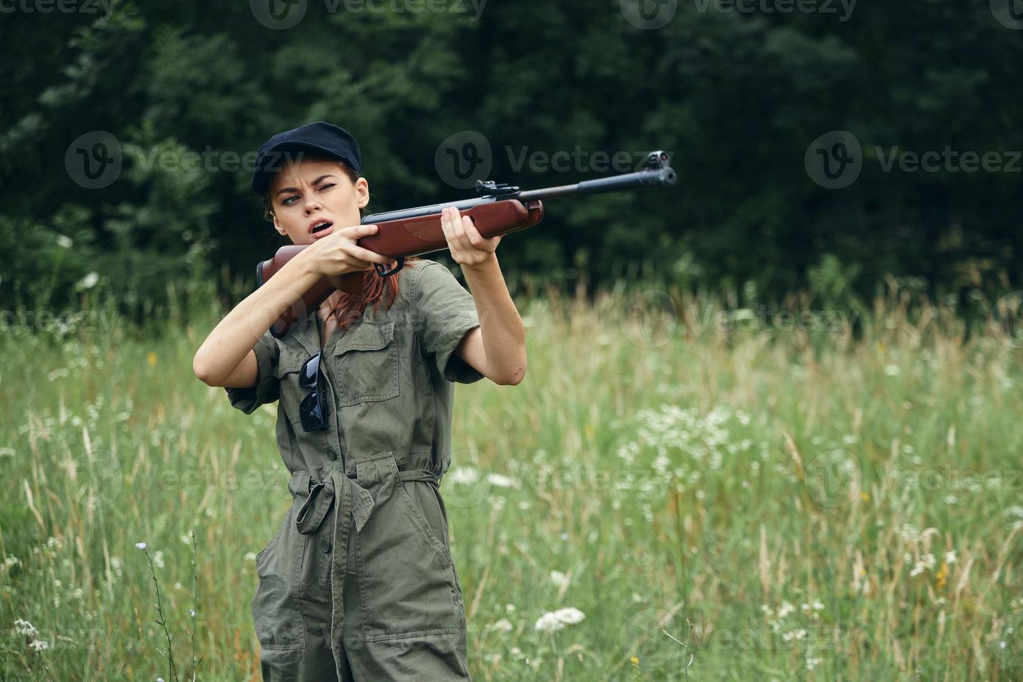 Frau auf Natur Jagd mit ein Gewehr im Grün Overall Grün Blätter foto