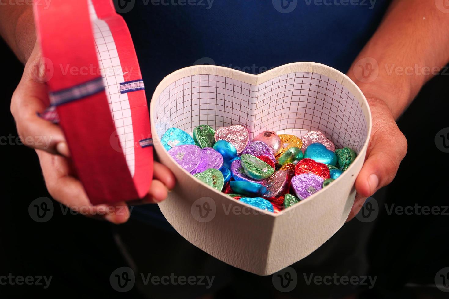 Herzform Geschenkbox mit Süßigkeiten isoliert auf schwarz foto