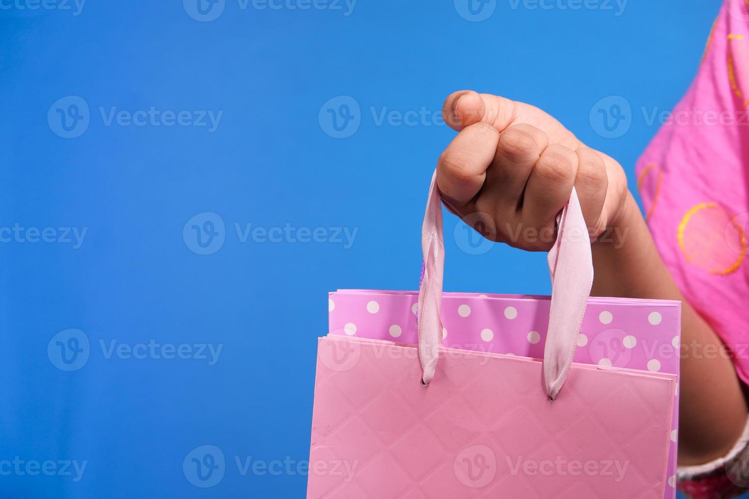 Frau, die rosa Einkaufstasche auf blauem Hintergrund hält foto