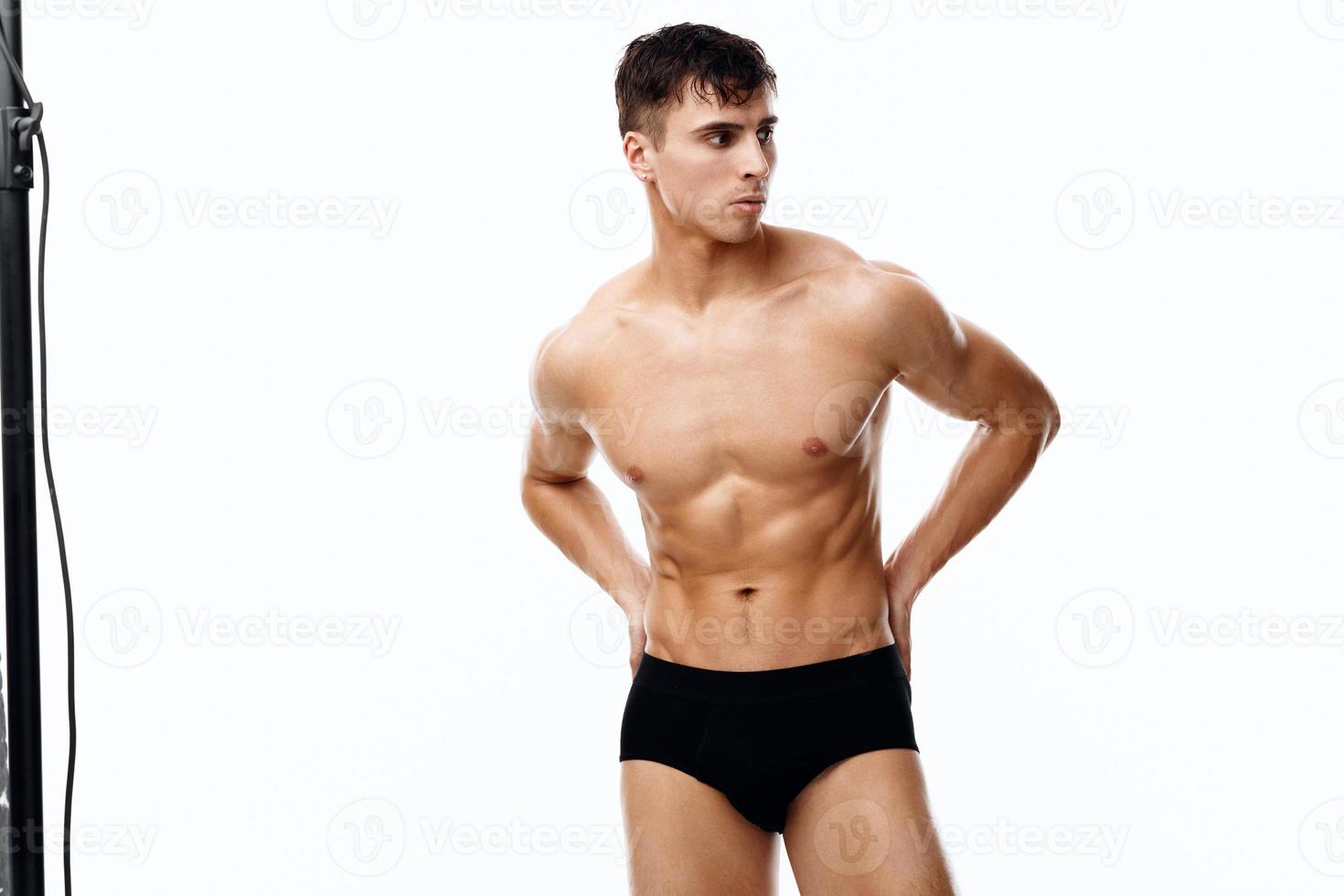ein Athlet mit ein sportlich Körperbau im schwarz kurze Hose Gesten mit seine Hände und sieht aus zu das Seite foto