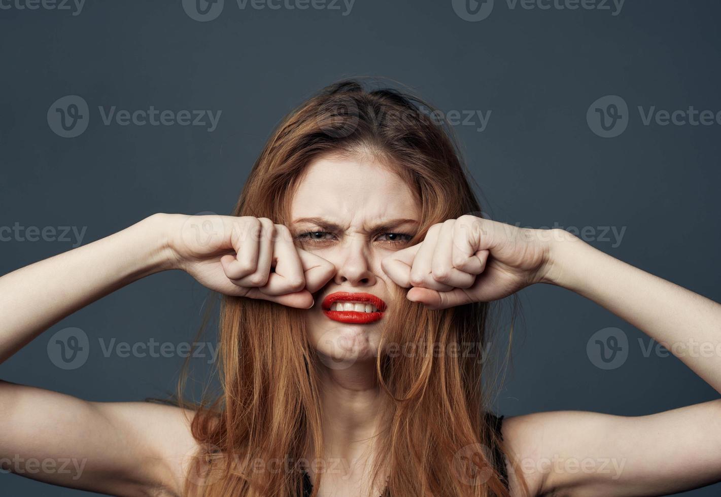 Frau mit rot Lippen Weinen auf grau Hintergrund und Hände in der Nähe von Gesicht abgeschnitten Aussicht foto
