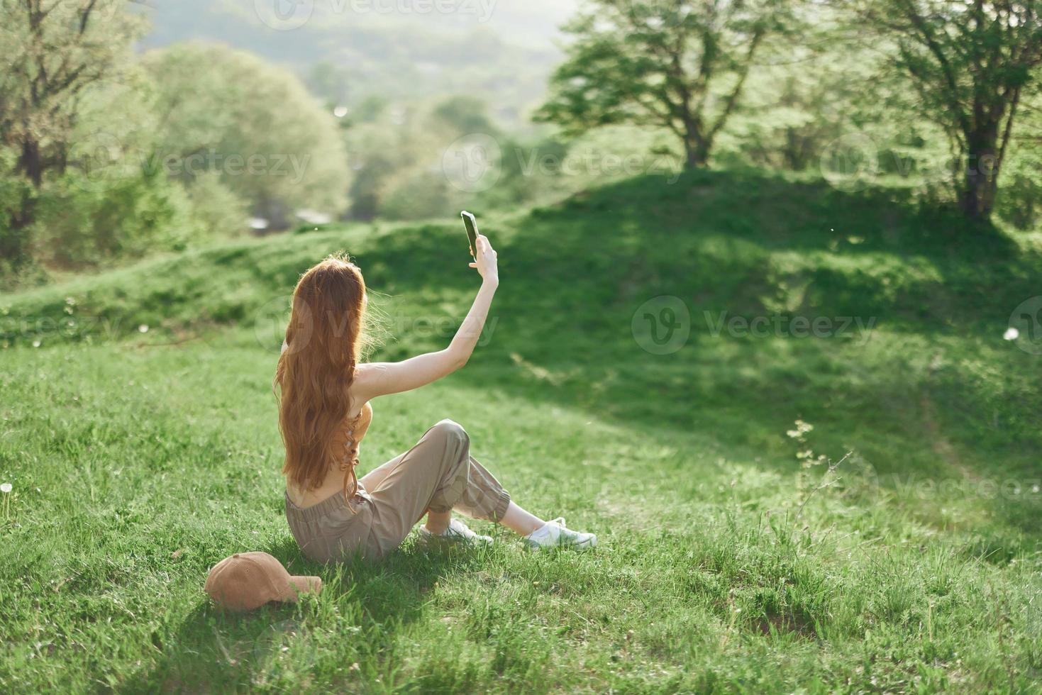 oben Aussicht von ein Frau mit Telefon im Hand freiberuflich Schüler versuchen zu finden Internet Verbindung im Natur im ein Grün Sommer- Park foto