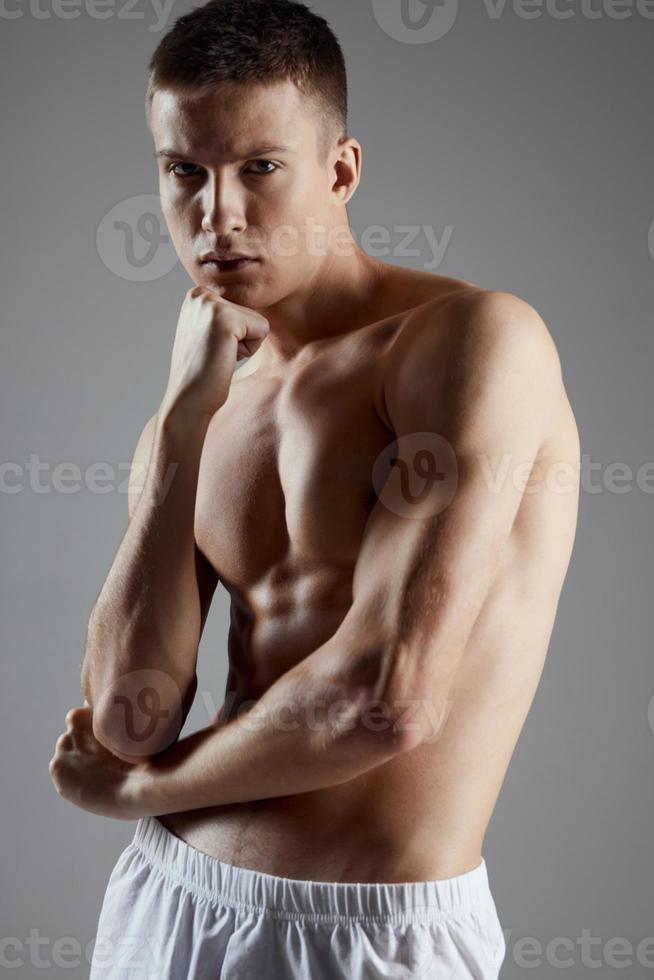 gut aussehend Sportler mit nackt Torso auf grau Hintergrund und Bizeps Bodybuilder Fitness foto