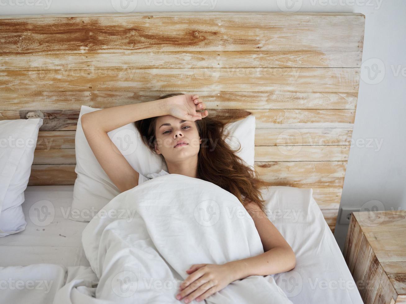 Frau halten ihr Hand auf ihr Stirn Lügen im Bett Gefühl nicht wohl foto