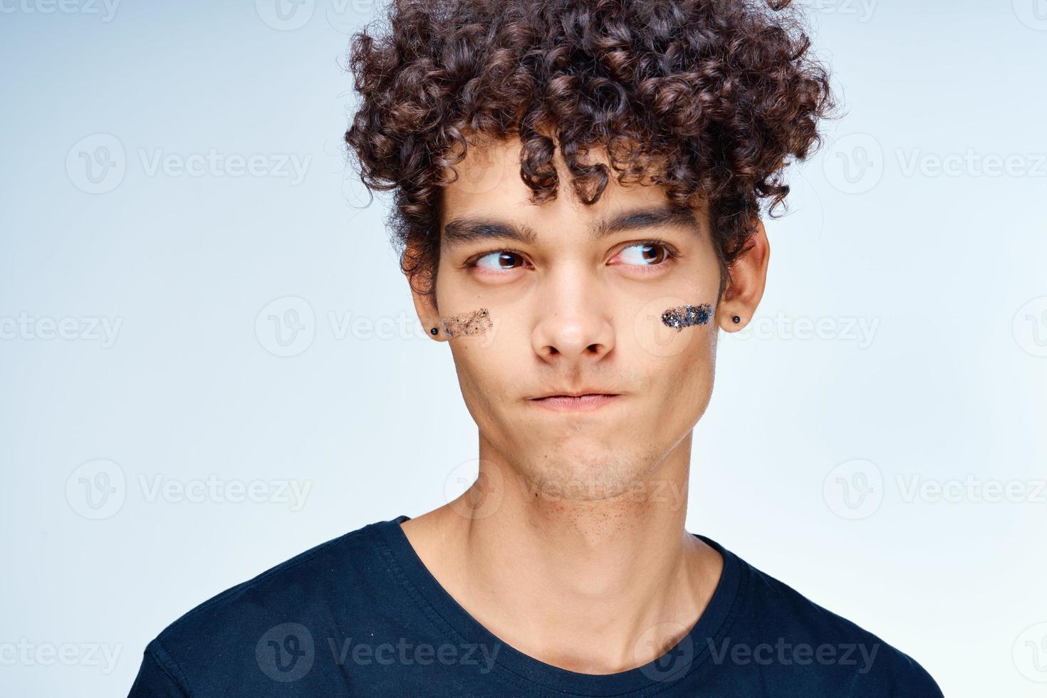 Kerl mit lockig Haar gilt ein schwarz Maske auf seine Gesicht Kosmetologie foto