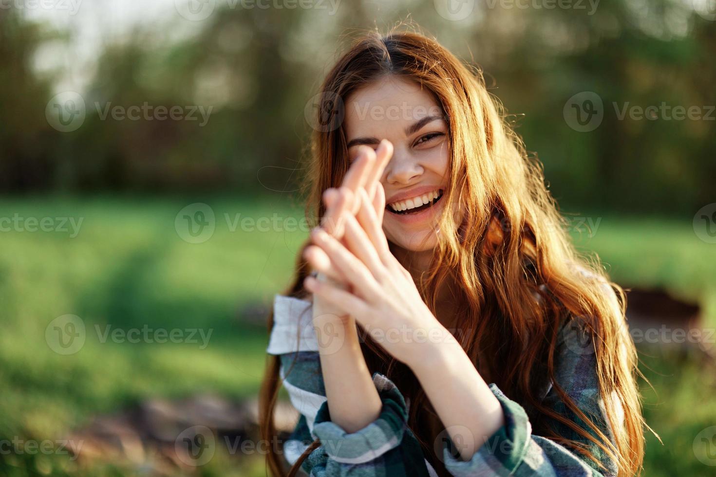 ein schön Frau draußen im ein Grün Park lacht und lächelt wie sie sieht aus in das Kamera beim Sonnenuntergang im das Sonne. Nahansicht Porträt foto