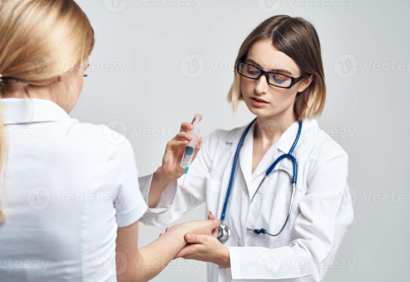 weiblich Arzt geben ein Injektion zu ein erschrocken weiblich geduldig im ein Weiß T-Shirt foto