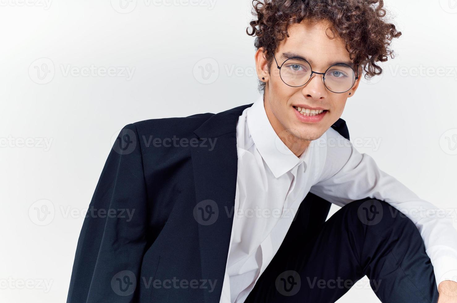 Porträt von ein lockiges Haar Kerl im ein Hemd im ein Jacke und Brille auf ein Licht Hintergrund Nahansicht foto