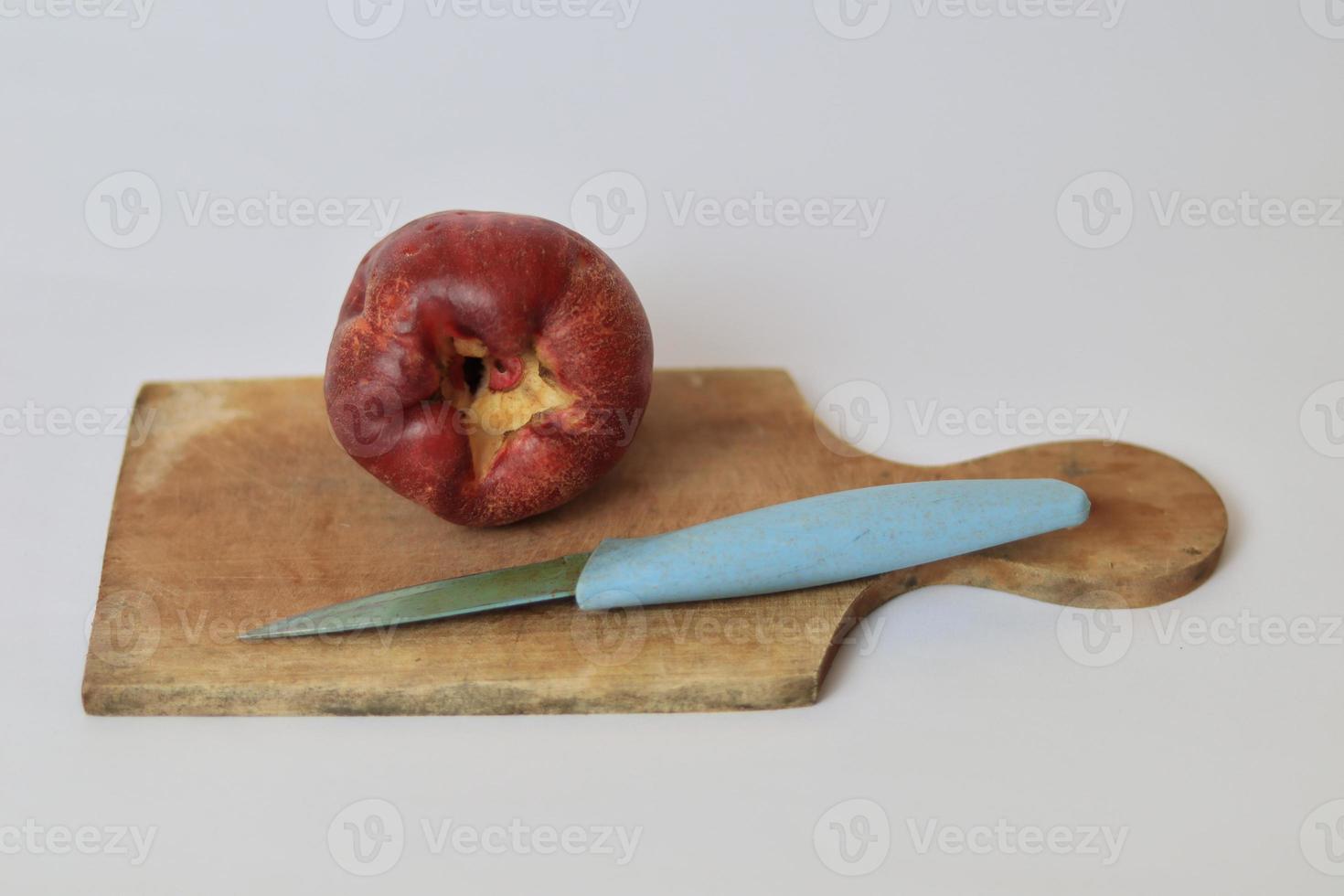 rot Jambu bol oder Jamaika Guave Nächster zu ein Blau Messer auf ein Schneiden Tafel gegen ein Weiß Hintergrund foto