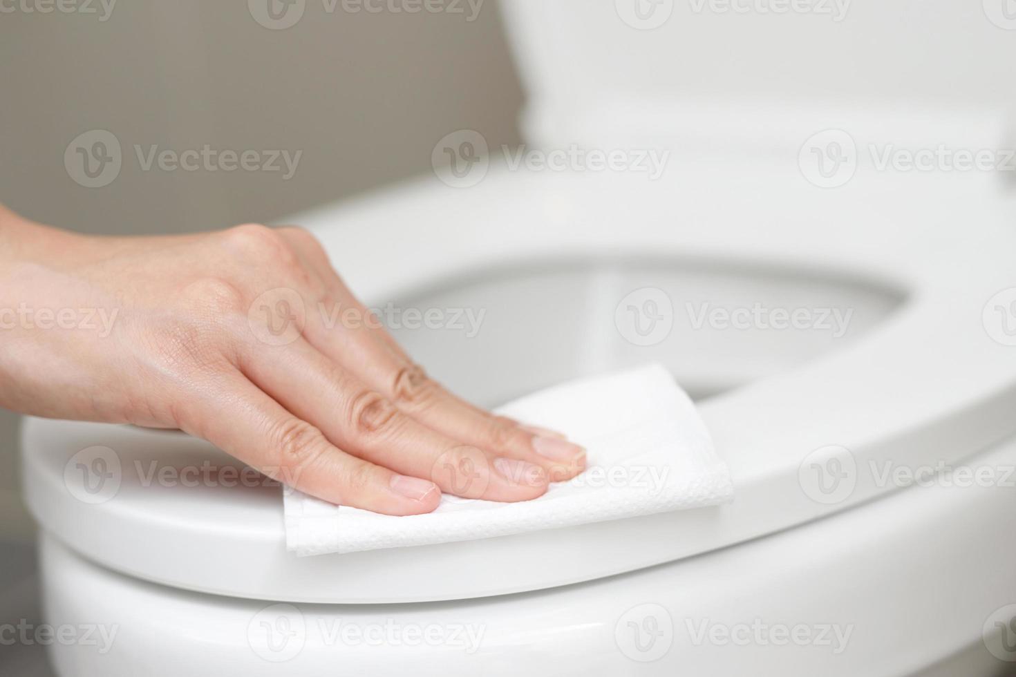 Frau mit Gewebe Papier sauber das Toilette im das Badezimmer beim heim. foto