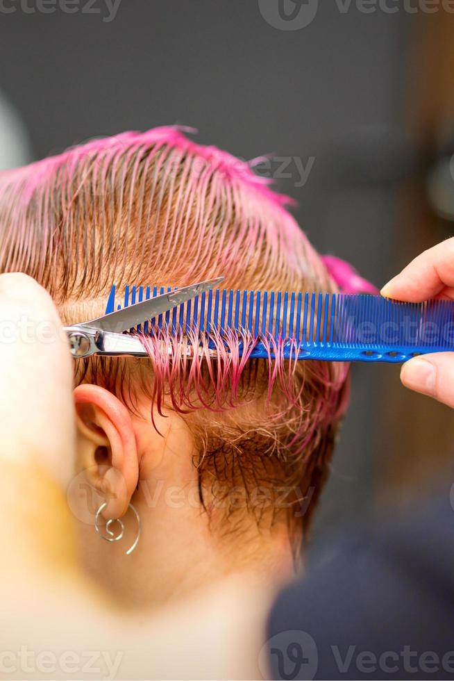 Frau mit Rosa Haar bekommen kurz Haarschnitt foto