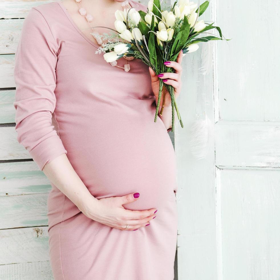 schwangere Frau, die weiße Blumen hält foto