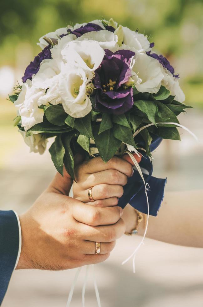 Paar hält einen weißen und lila Blumenstrauß foto