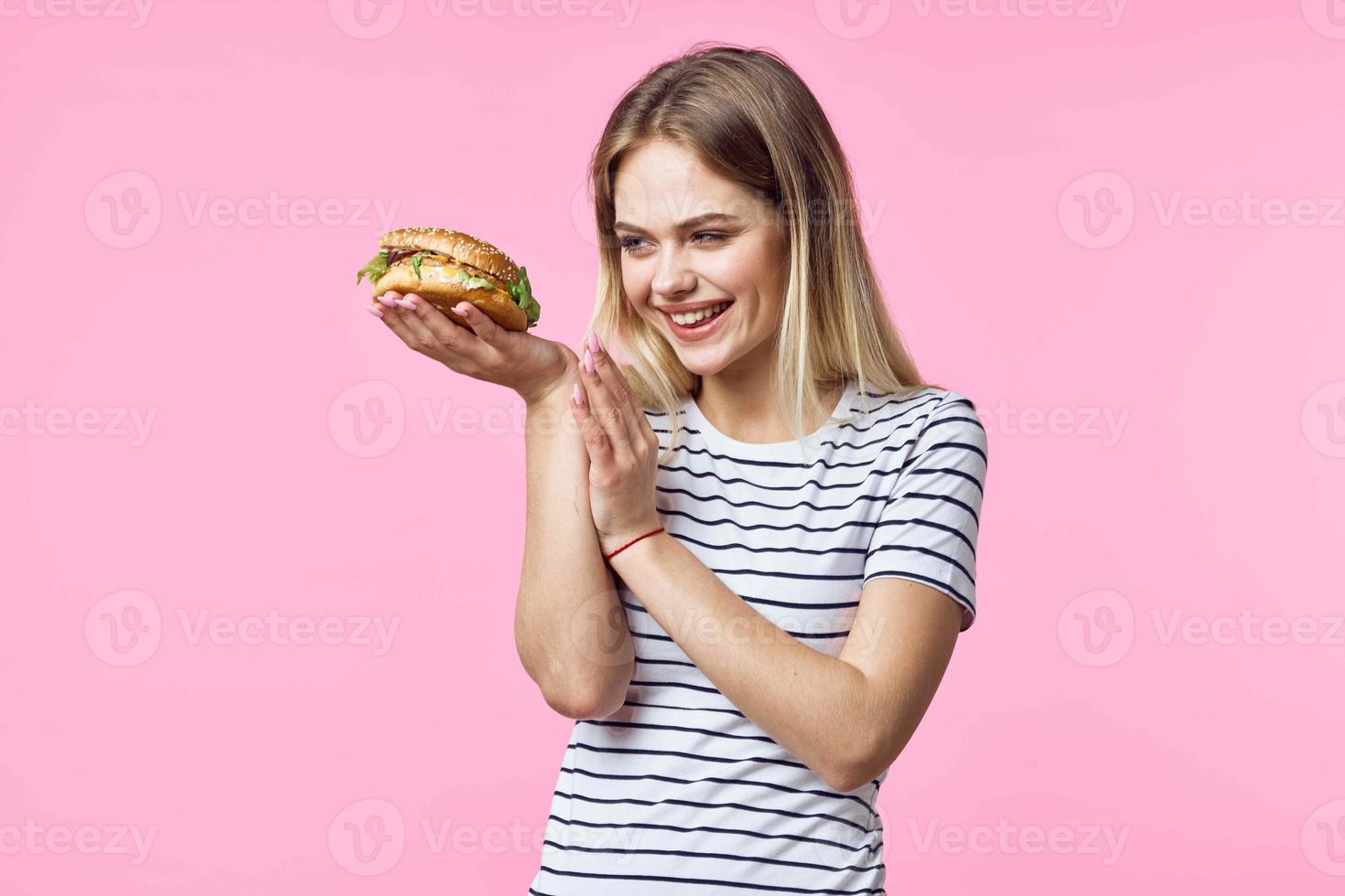 süß blond Mädchen im gestreift T-Shirt Hamburger Nahansicht schnell Essen Lebensstil foto