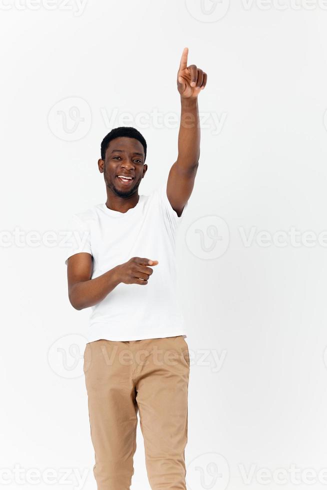 afrikanisch amerikanisch im ein Weiß T-Shirt Gesten mit seine Hände Emotionen Licht Hintergrund foto