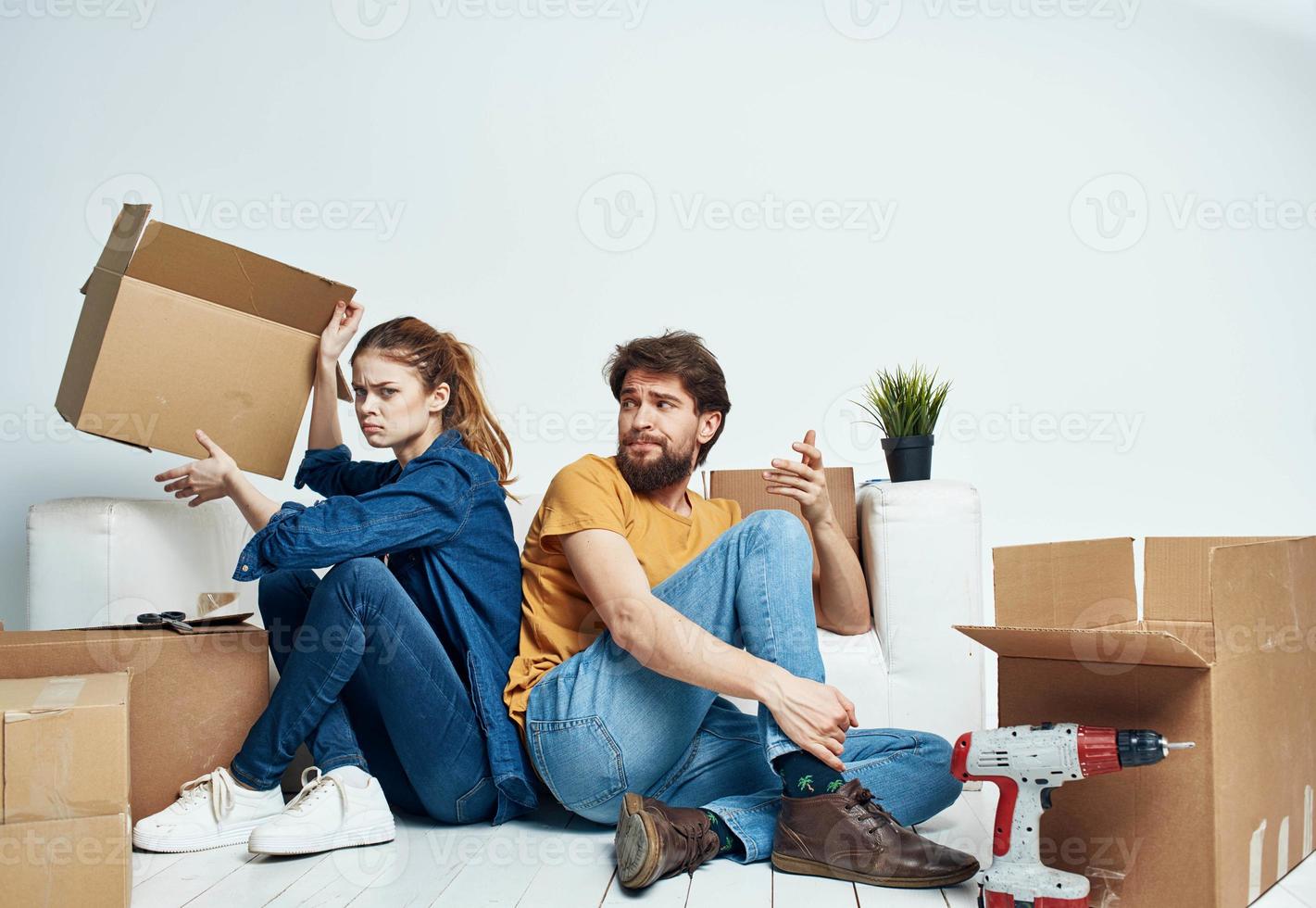 Mann und Frau Sitzung auf das Fußboden mit ihr Rücken zu jeder andere Renovierung Arbeit ziehen um ein Blume im ein Topf foto