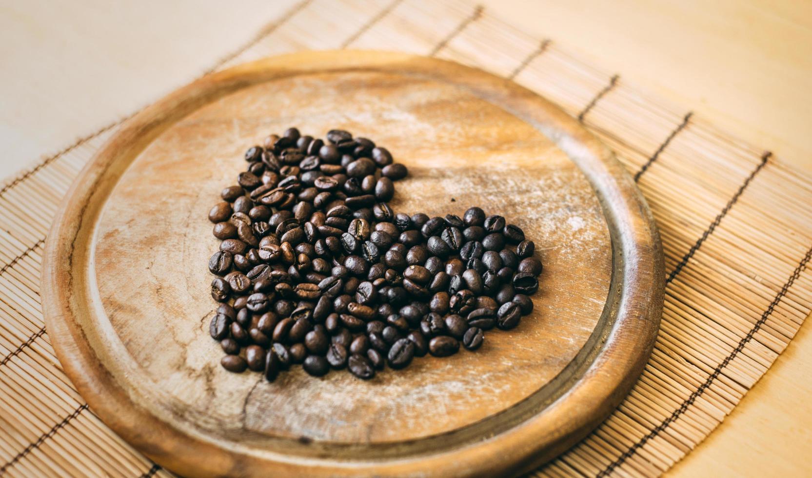 Kaffeebohnen auf einem Holzbrett in Herzform foto