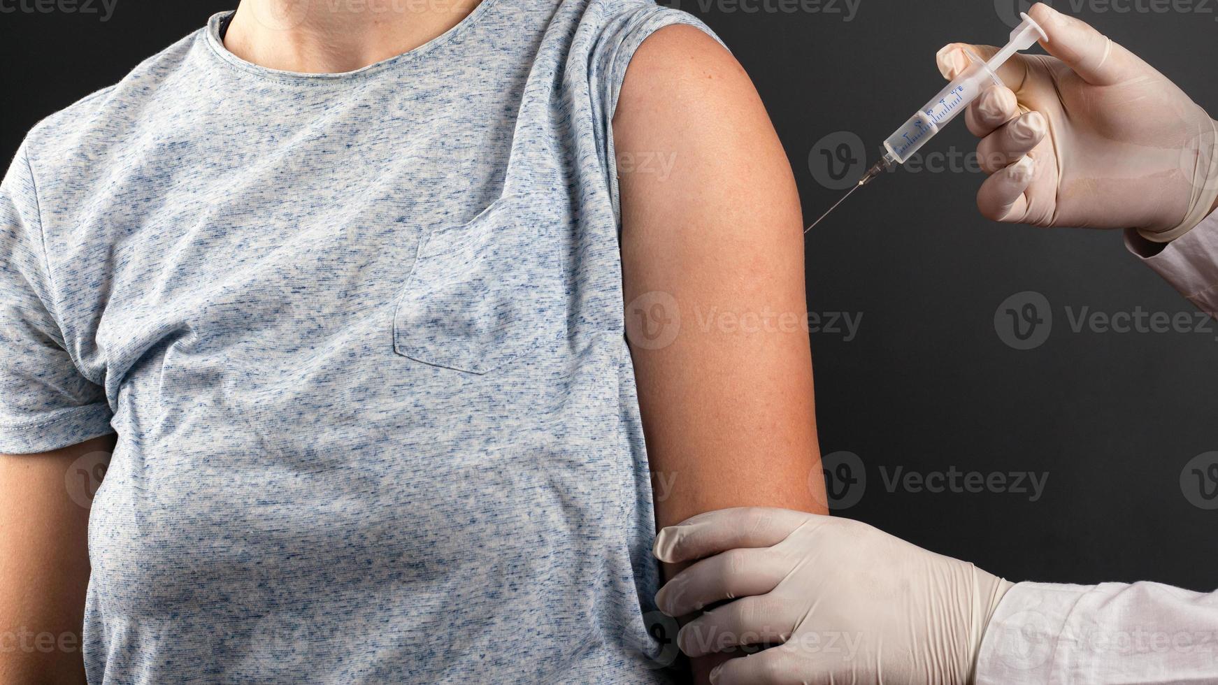 Der Arzt injiziert einen Impfstoff aus Covid-19 foto