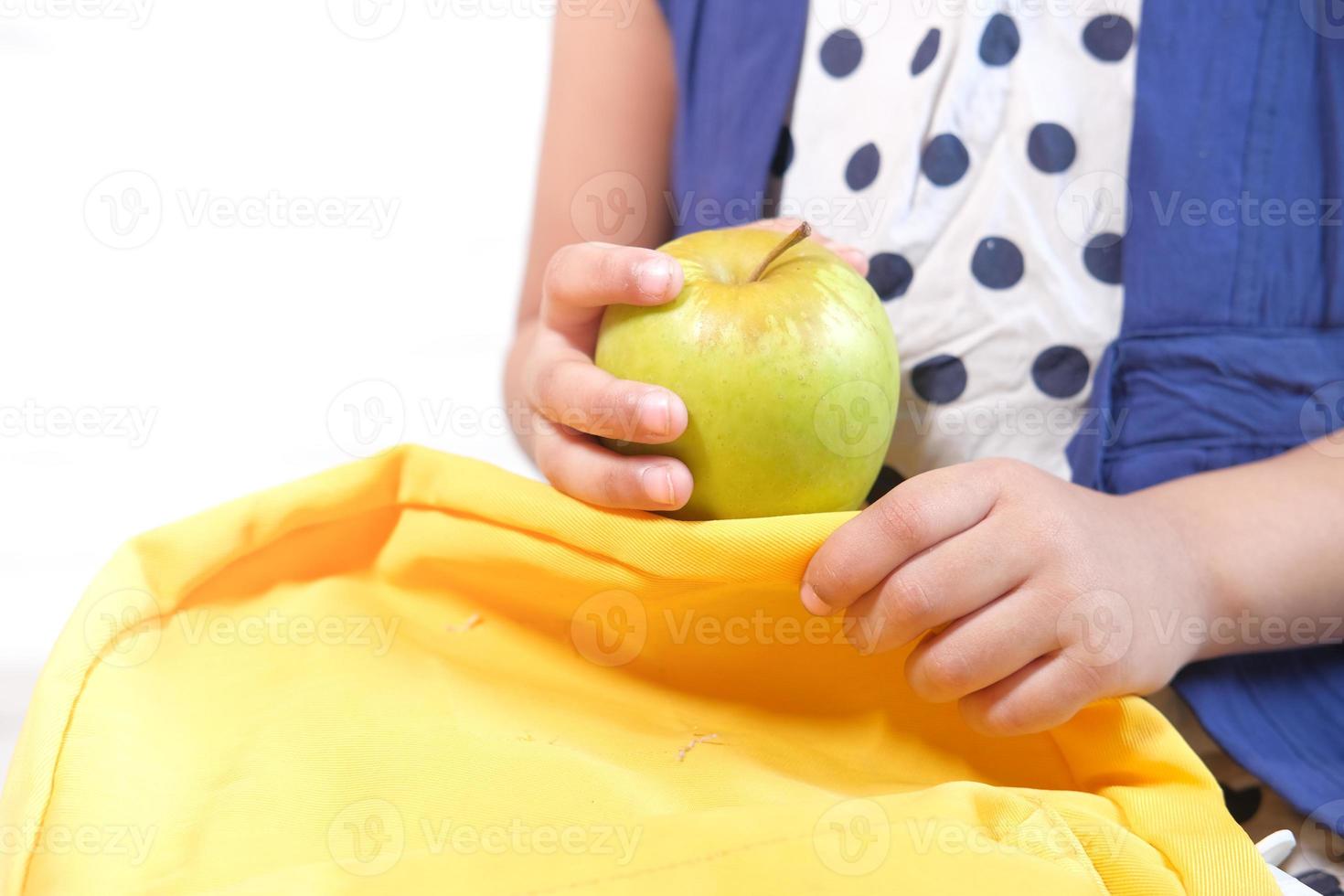 Kind, das grünen Apfel auf weißem Hintergrund hält foto