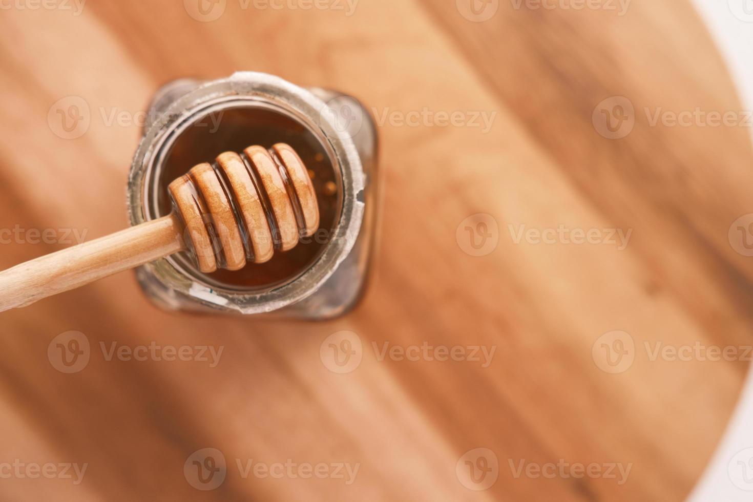 frischer Honig mit Schöpflöffel auf Holztisch foto