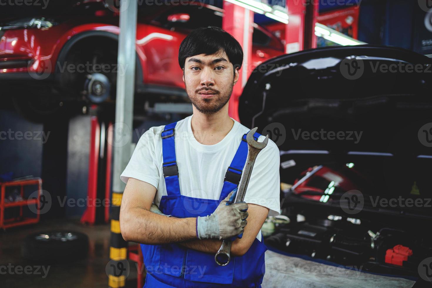 asiatisch Mechaniker Überprüfung das Sicherheit von ein Wagen. Instandhaltung von beschädigt Teile im das Garage. Instandhaltung Instandsetzung. Reparatur Bedienung Konzept. foto