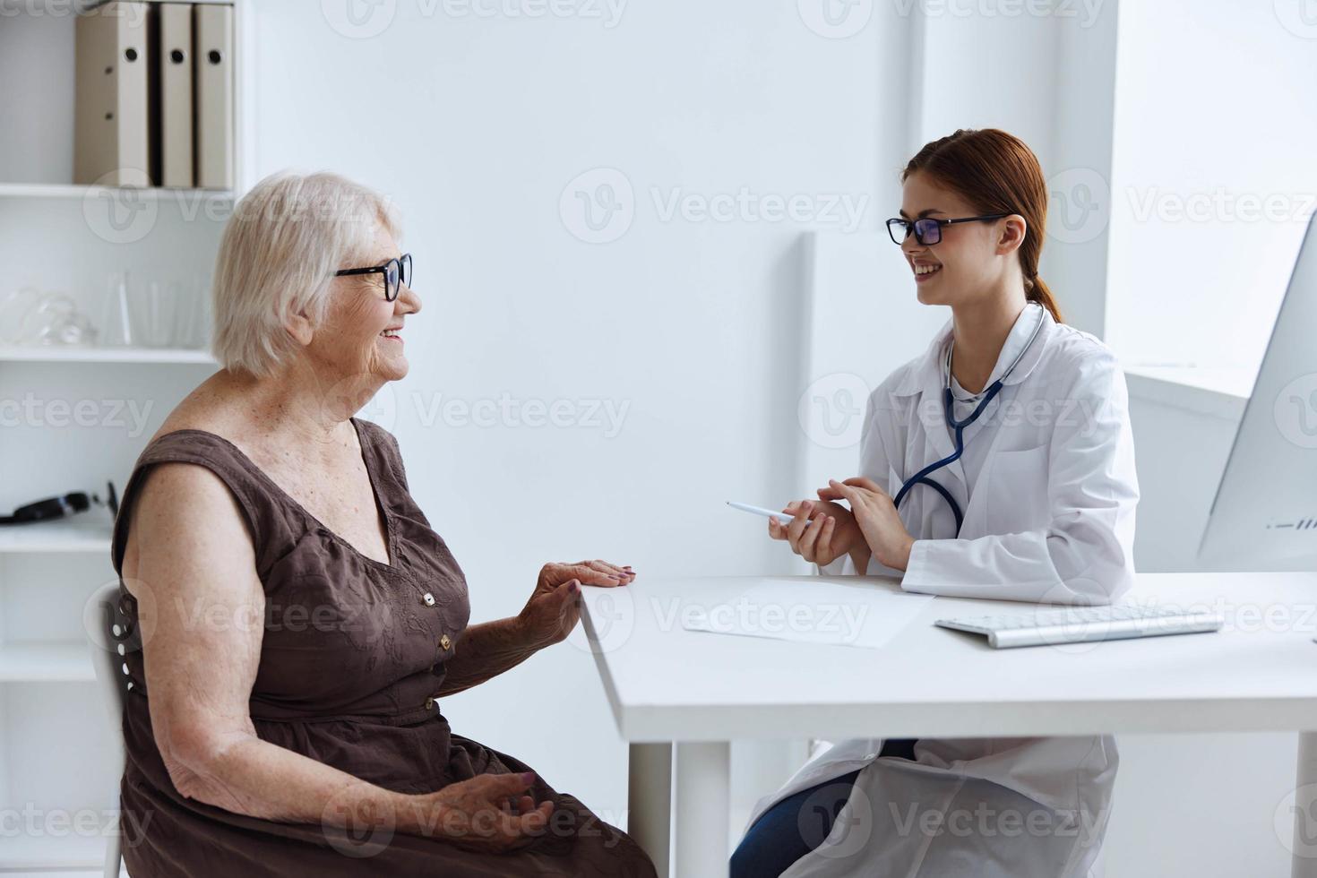 Alten Frau mit Brille kommuniziert mit das Arzt Gesundheit Pflege foto