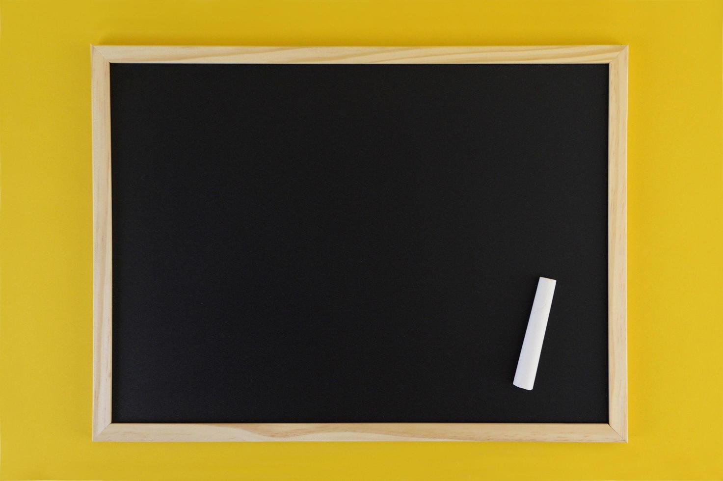 leere schwarze Tafel auf gelbem Hintergrund. Vorderansicht auf schwarzer Tafel mit Holzrahmen. leerer Kopierplatz auf dem Flachbildschirm. foto