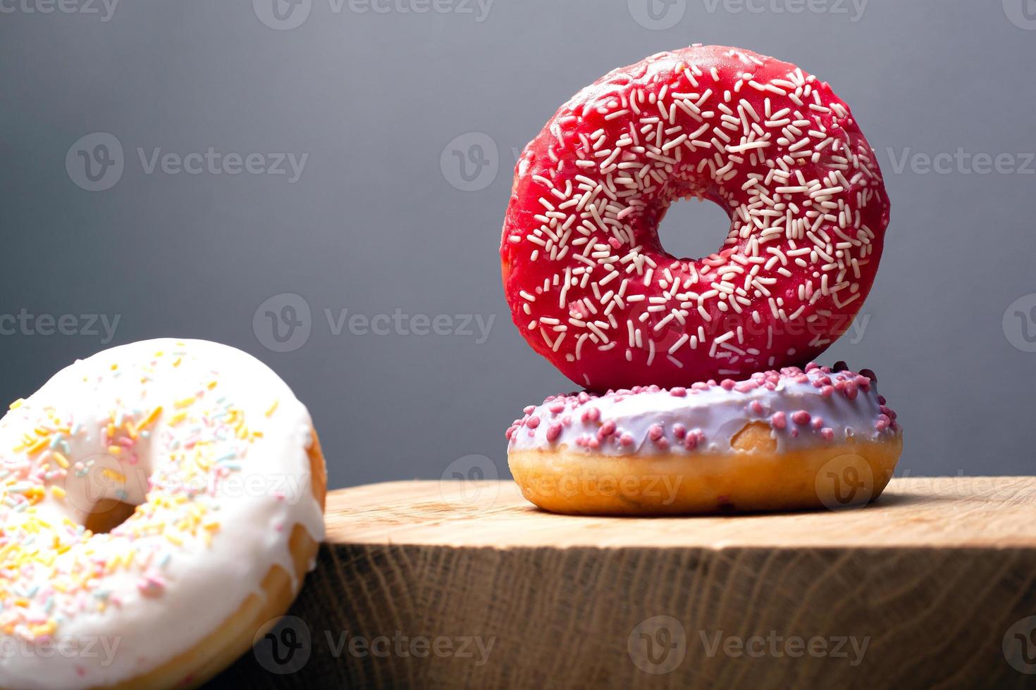 Feiertagskrapfen mit violetter und roter Glasur auf grauem Hintergrund foto