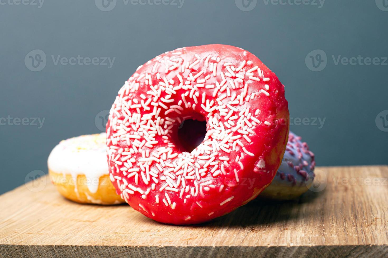 köstlich leckerer roter Donut mit weißem Pulver auf einem Holzständer auf grauem Hintergrund foto