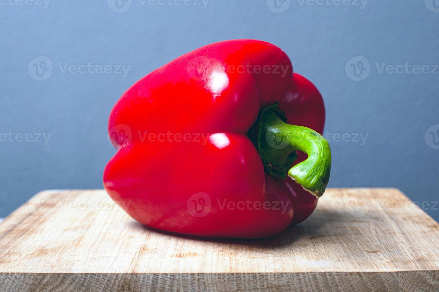 große rote Paprika auf einem Holzständer auf einem grauen Hintergrund foto