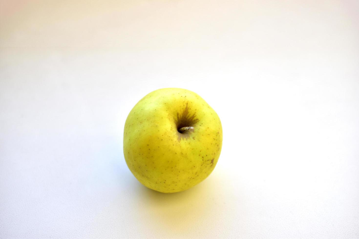 gelbgrüner Apfel auf einem weißen Hintergrund schließen oben foto