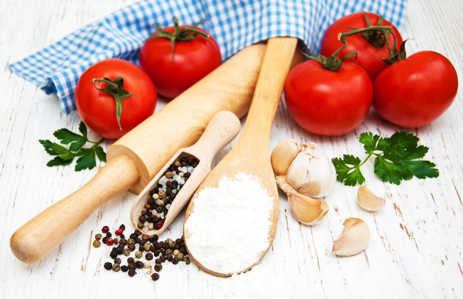 Tomate, Knoblauch und Mehl auf einem hölzernen Hintergrund foto