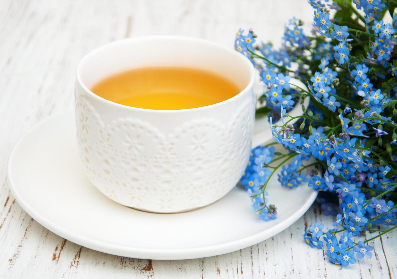 Tasse Tee und vergiss mich nicht Blumen auf einem hölzernen Hintergrund foto