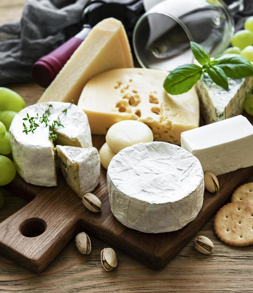 verschiedene Arten von Käse, Trauben und Wein auf einem Holztisch foto