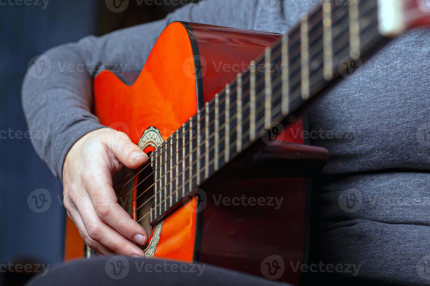 Mädchen spielt eine orangefarbene Akustikgitarre mit Nylonsaiten foto