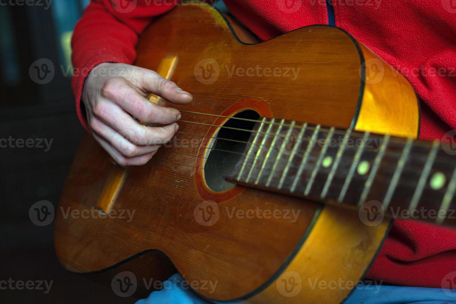 Musiker in Rot spielt eine Akustikgitarre foto