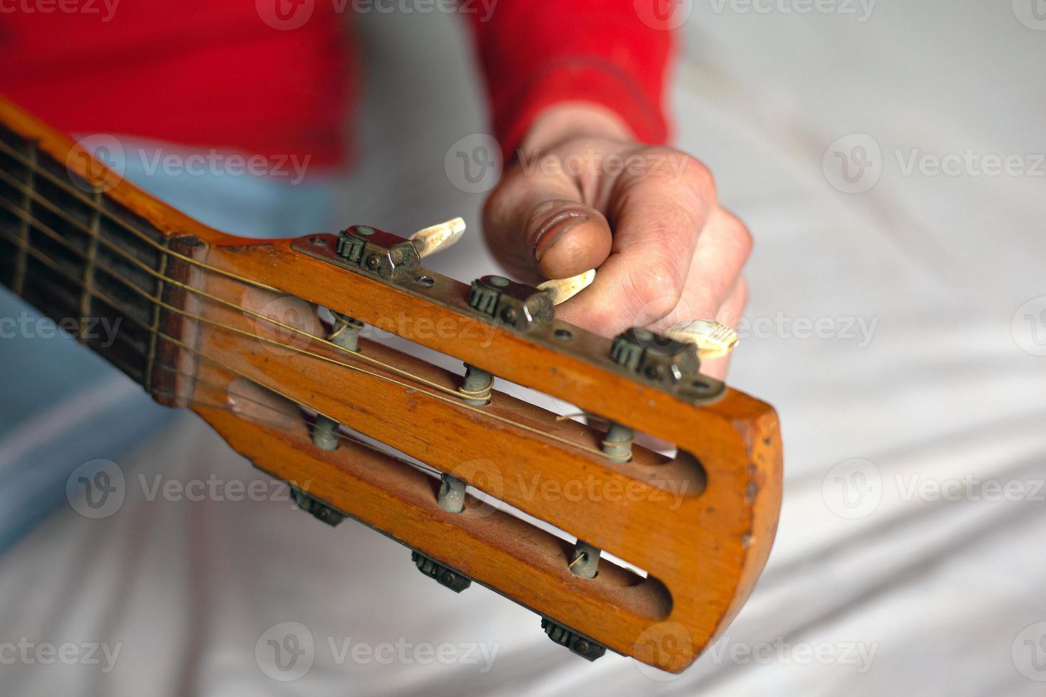 Musikerhand dreht die Melodien der Gitarre und stimmt das Instrument foto