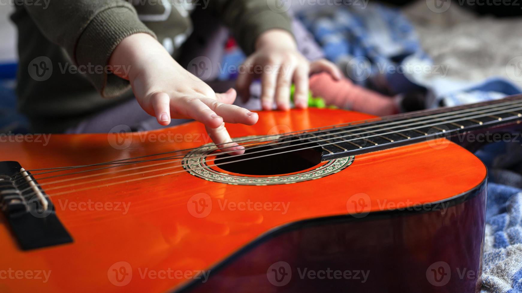 Kind spielt auf akustischen Gitarrensaiten foto