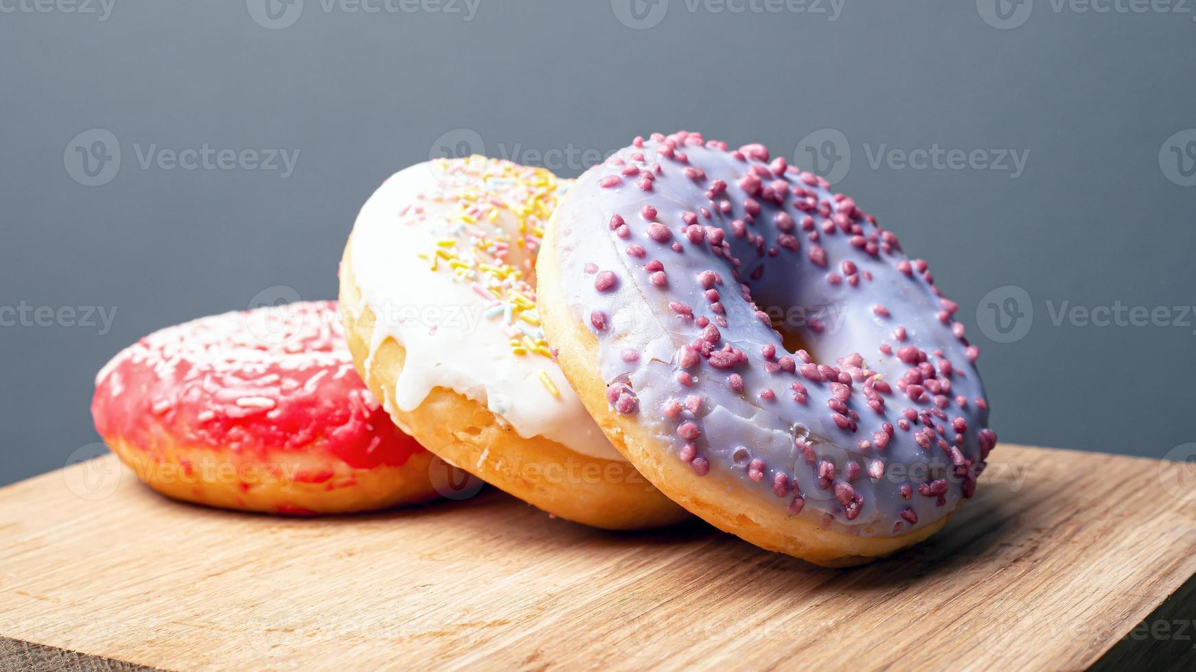leckere Donuts mit mehrfarbiger Glasur von roter weißer und violetter Farbe mit Puder foto