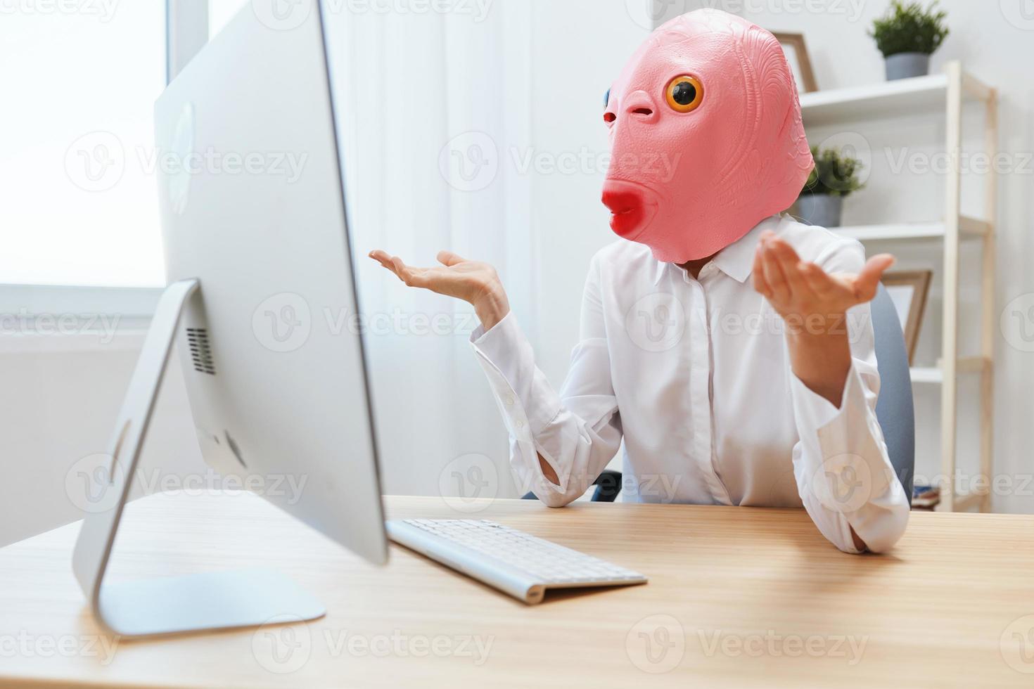 wütend komisch verrückt Geschäftsfrau Arbeiter Freiberufler im Rosa Fisch Maske Arbeit auf Computer online Nachdenken oder Herstellung Entscheidung schockiert durch betriebsbereit Probleme Verbreitung Hände im Licht modern Büro. Kopieren Raum foto