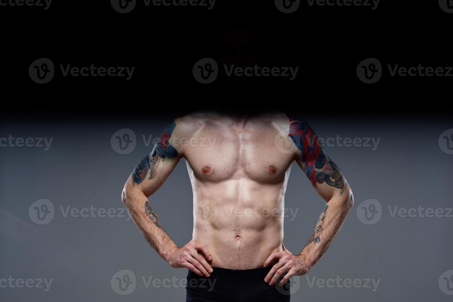 sportlich Mann gepumpt oben Drücken Sie Schauspielkunst aus auf seine Waffen abgeschnitten Aussicht grau Hintergrund foto