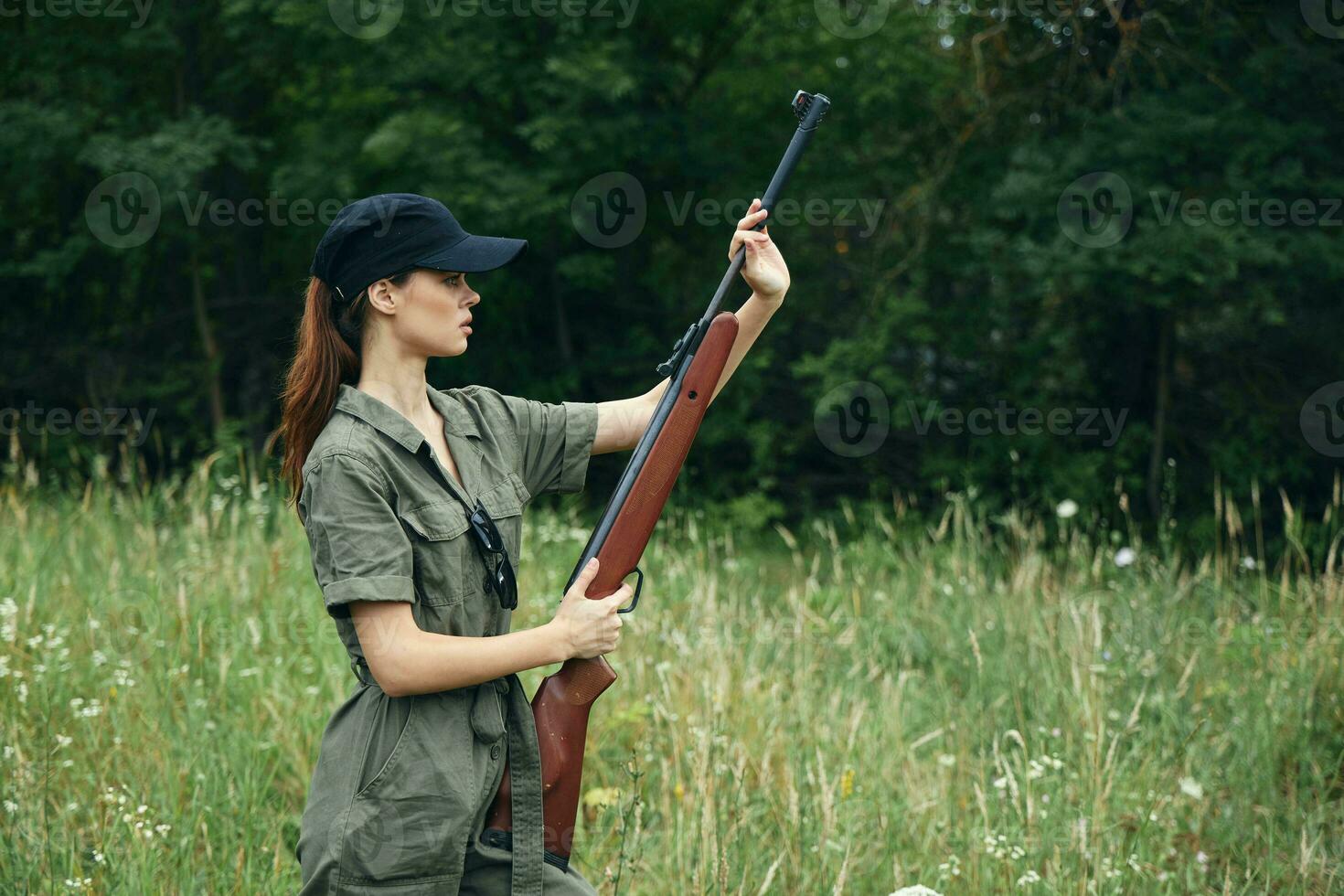 Frau auf Natur mit ein Gewehr im seine Hände schwarz Deckel Grün Overall Schießen frisch Luft foto