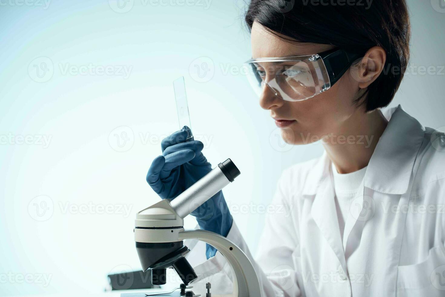 Frau Wissenschaftler im ein Weiß Mantel suchen durch ein Mikroskop Studie foto