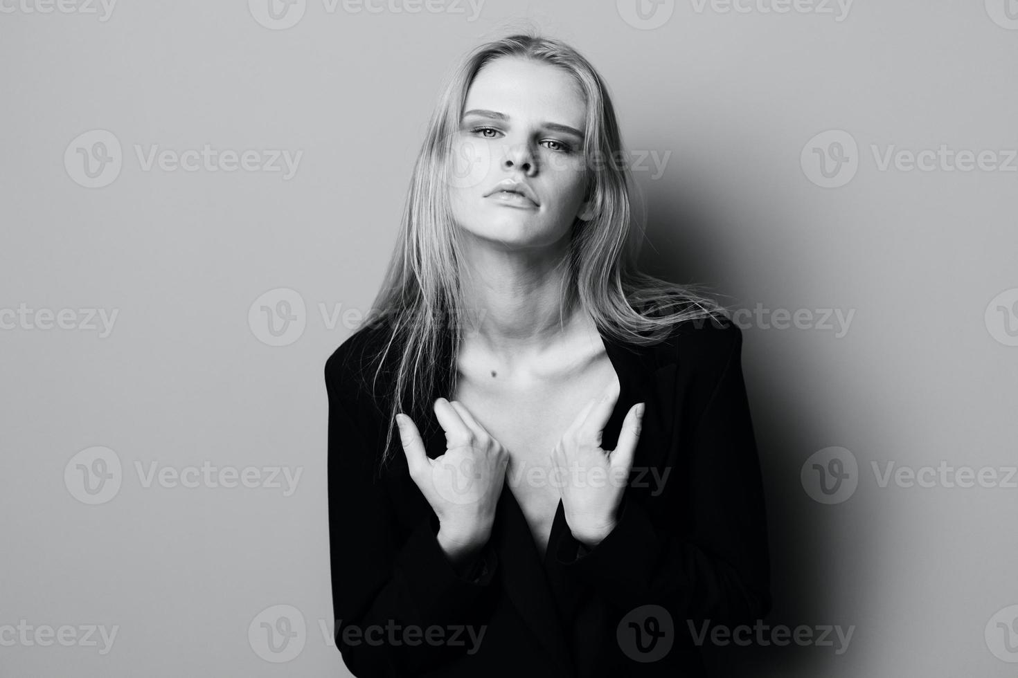 Herrlich jung stilvoll Dame im Jacke posieren gelehnt auf das Mauer beim Studio. ziemlich weiblich blond Modell- sexy suchen beim Kamera foto