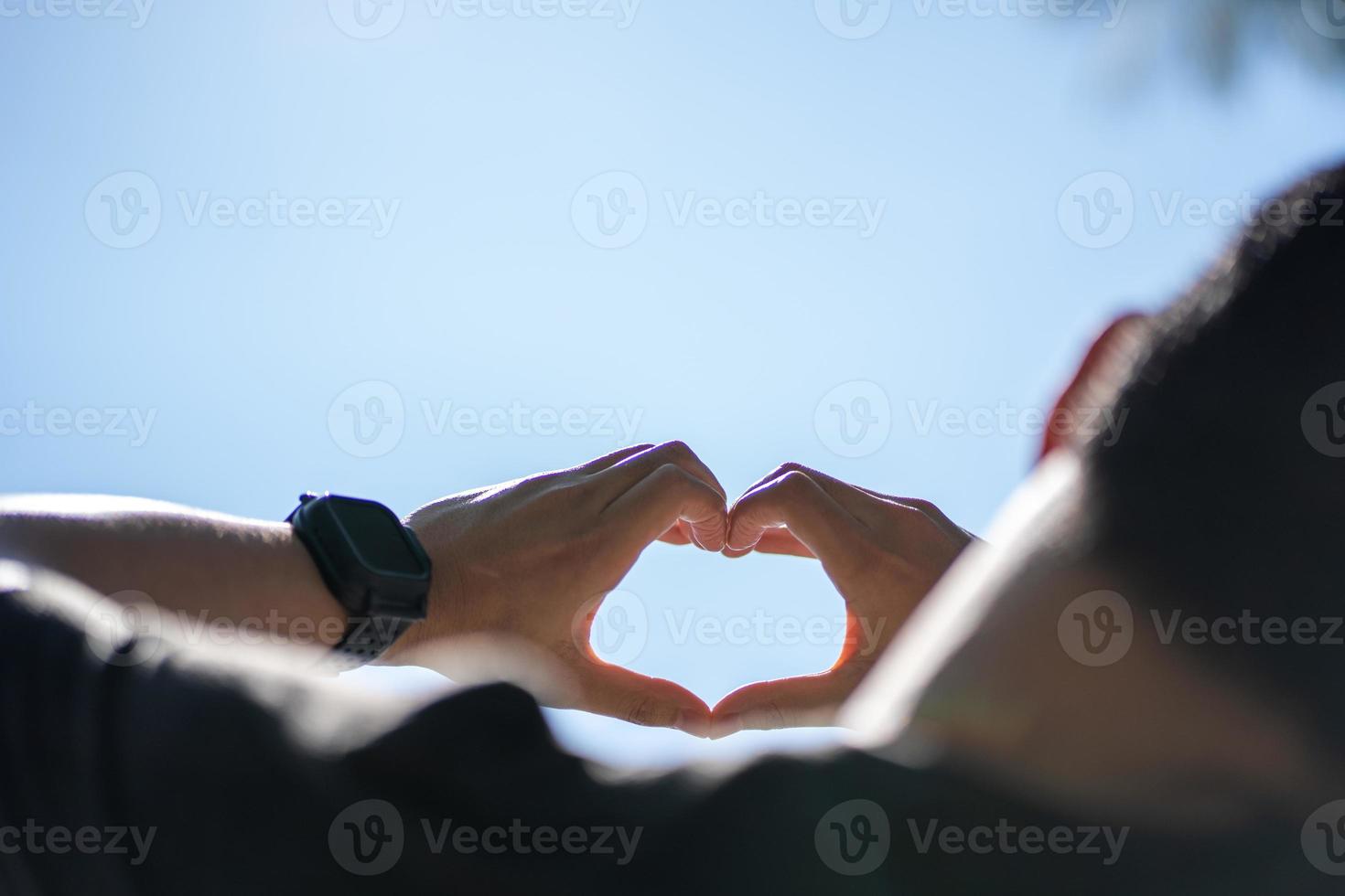 männlich Hände im das gestalten von ein Herz auf das Himmel wie Hintergrund. foto
