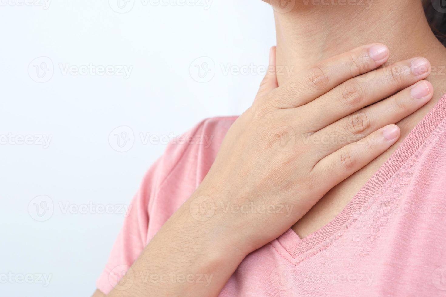 wund Kehle Schmerz. Nahansicht von jung Frau krank halten ihr entzündet Kehle mit Hände zu berühren das krank Hals im Blau Hemd auf grau Hintergrund. medizinisch und Gesundheitswesen Konzept. Fokus rot auf zu Show Schmerz. foto