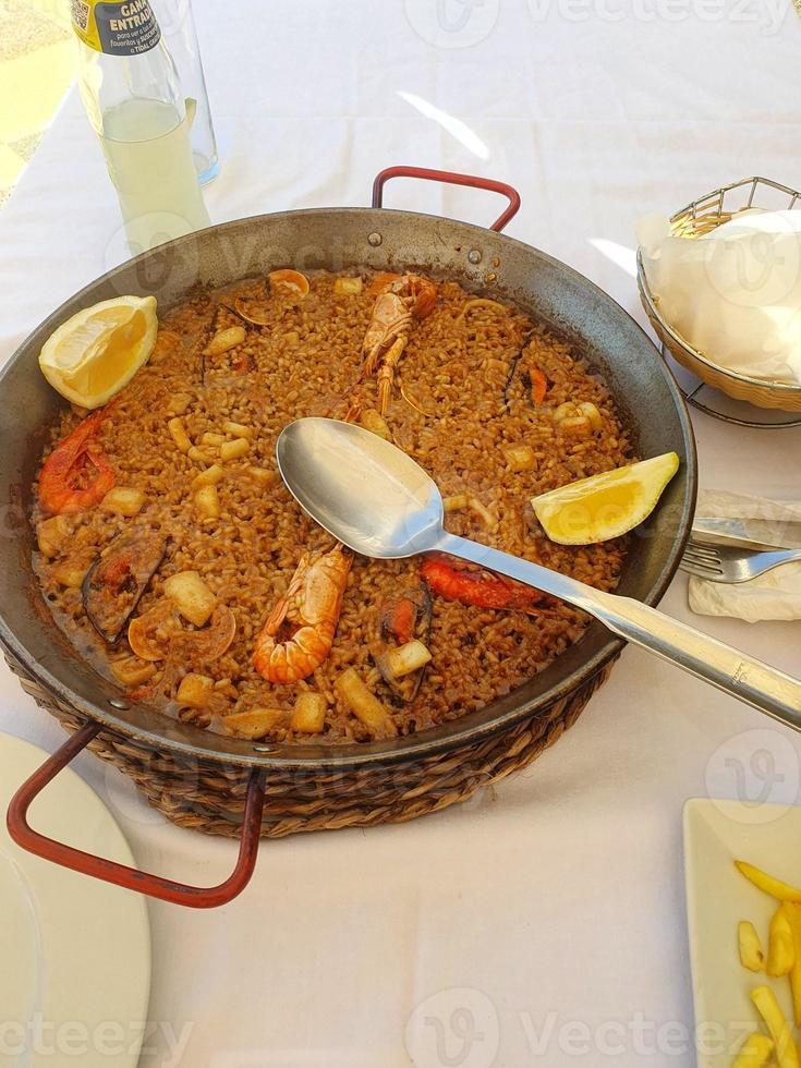 heiß Spanisch Paella mit Meeresfrüchte und Garnelen und ein Löffel foto